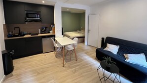 A compact living space with a kitchenette, a dining area, and a seating area with a sofa and a small table. - Superb studio with sleeping area! Old Nice! (Nice)