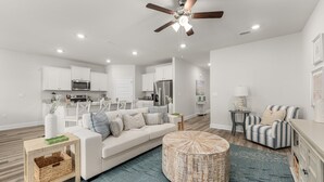 A modern living room with a white sofa, a round coffee table, and a striped armchair. - Fall Break, Family Friendly, Walk2Beach & Pools, Golf Cart, 4BR, 2 Kings (Port St. Joe)