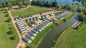 Ett flygbildsbild av en campingplats med husbilar och husvagnar uppställda i rader längs en flod.