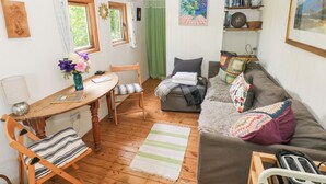 Ein gemütliches Zimmer mit Holzboden, einem Esstisch mit Stühlen, einer Couch und einem Bücherregal.