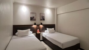 A hotel room with two single beds, a nightstand with a lamp, and two wall-mounted picture frames. - Hotel Harmony (Batulicin)