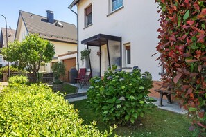 Una propiedad residencial con un patio, una zona de estar exterior cubierta y un jardín bien cuidado.
