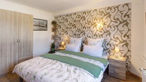 Une chambre à coucher avec un lit, des tables de chevet, une armoire et un papier peint à motifs.