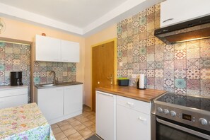Una cocina compacta con cafetera, pileta, estufa y una puerta.