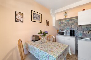 Una cocina con salpicadero de azulejos, un microondas, un tostador y un florero con flores sobre la mesa.