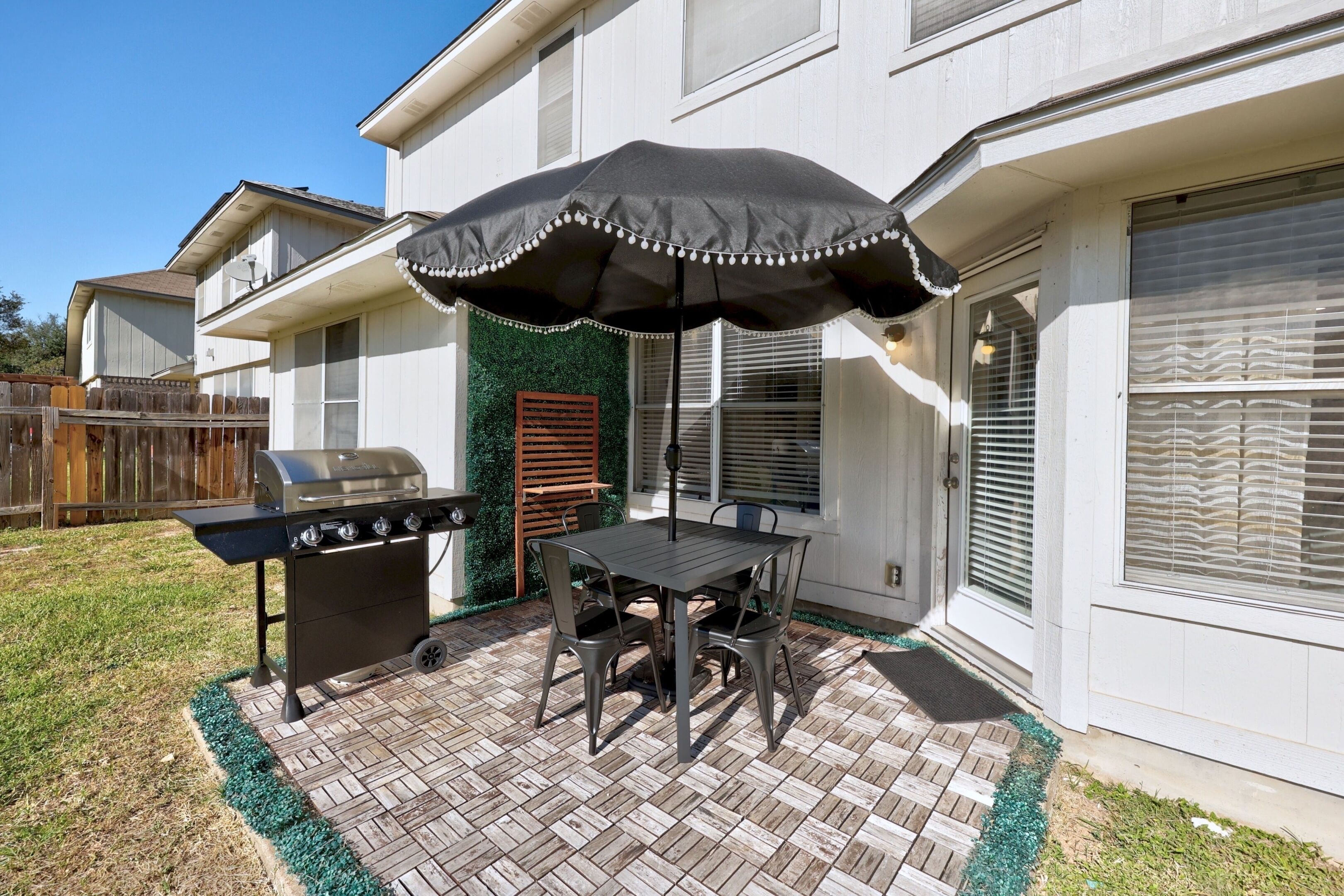A patio with a grill, table, and umbrella.