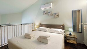 A neatly made bed with towels, a bedside lamp, and a wall-mounted air conditioner. - Romito Loft by MMega (Florence)