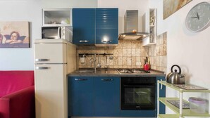 A compact kitchen with blue cabinets, a white refrigerator, a stove, and a dishwasher. - Romito Loft by MMega (Florence)
