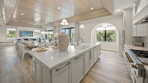 A spacious kitchen with a large island, modern appliances, and large windows offering views.