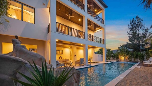 A multi-story building with a swimming pool, outdoor seating, and a large rock feature.