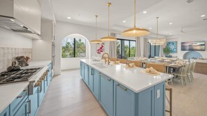 Une cuisine moderne avec des armoires bleues, un grand îlot central et des luminaires suspendus.