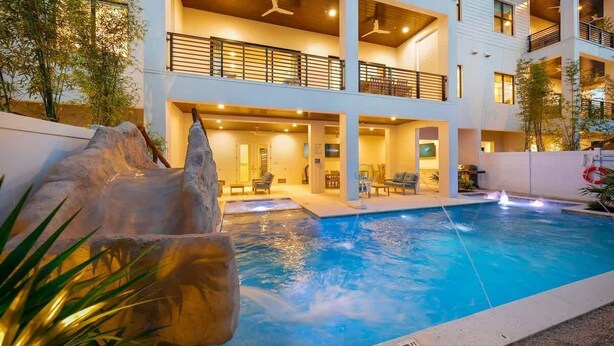 Un hôtel à plusieurs étages doté d’une piscine, d’un espace extérieur aménagé et d’une cascade.