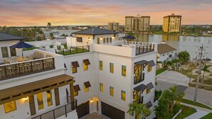 A multi-story hotel with balconies, outdoor seating, and a view of a body of water. - New-Endless Amenities-Unmatched Rooftop & Views (Clearwater)