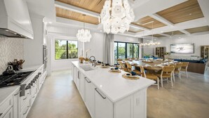 A spacious kitchen with a large island, modern appliances, and a dining area with a large table and chairs. - New-Endless Amenities-Unmatched Rooftop & Views (Clearwater)
