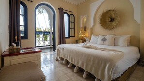 A bedroom with a large bed, a bedside table, a nightstand, and a view of the outside balcony. - Riad Come&va (Marrakech)