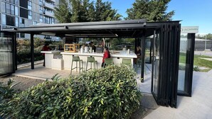 Een terras met glazen wanden, een balie en zitplaatsen.