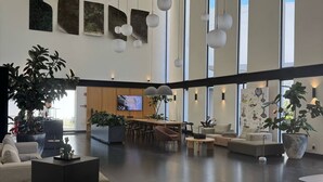 A spacious lobby with high ceilings, large windows, and modern furniture.