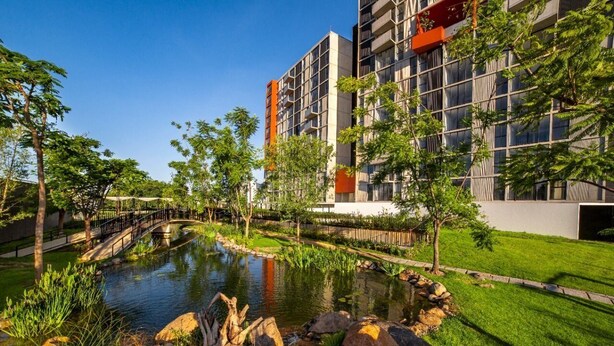 Un bâtiment moderne doté d’un jardin aménagé, d’un petit étang et d’un pont.