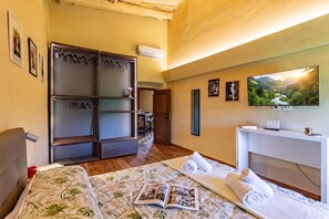 A hotel room with a bed, a desk, a TV, and a wardrobe. - Romantic Apartment In Chianti Classico (Castelnuovo Berardenga)