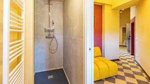 A modern bathroom with a shower, a yellow chair, and a checkered floor. - Romantic Apartment In Chianti Classico (Castelnuovo Berardenga)
