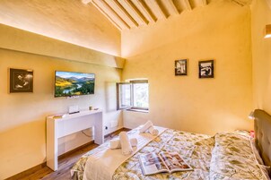 Un dormitorio con una cama, un escritorio, un televisor y cuadros en la pared.
