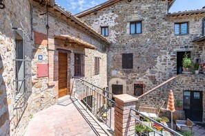 A stone building with a staircase leading to a balcony with outdoor seating. - Romantic Apartment In Chianti Classico (Castelnuovo Berardenga)
