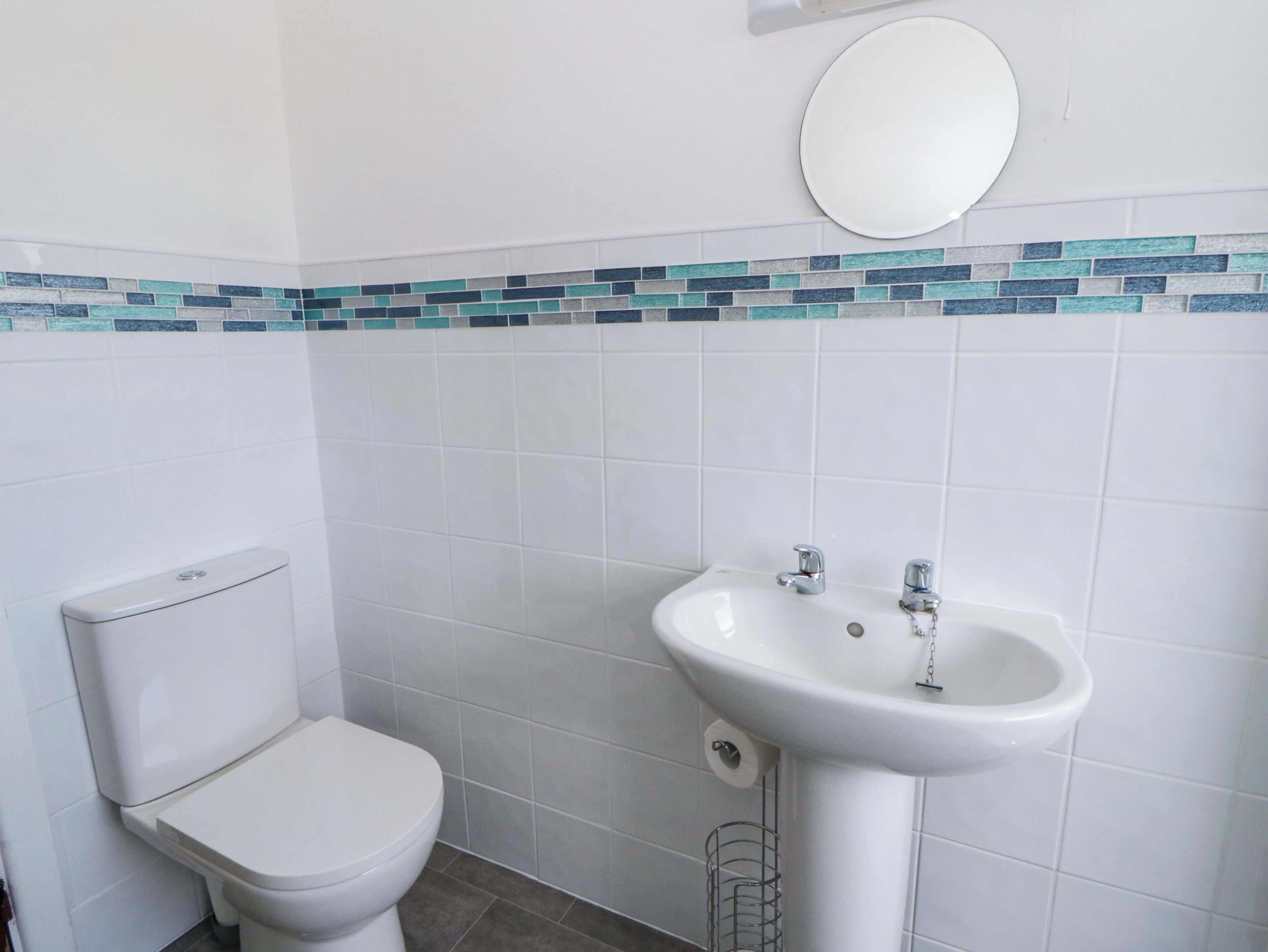 A bathroom with a toilet, a sink, and a mirror.
