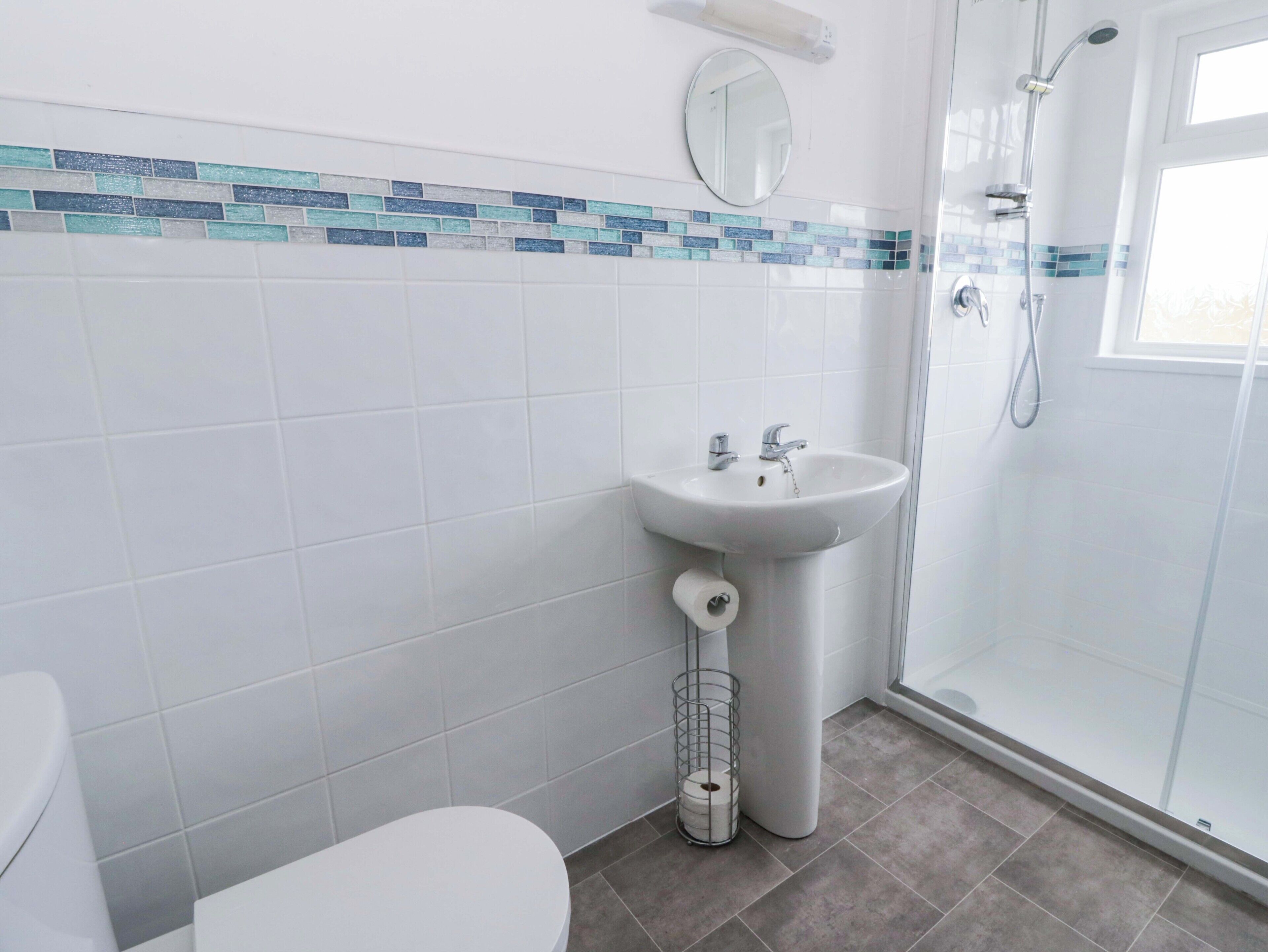 Un baño con inodoro, lavamanos, ducha y espejo.