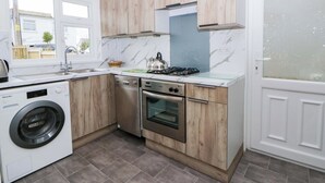 Una cocina compacta con lavadora, estufa a gas y horno empotrado.