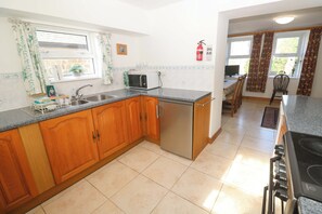 A kitchen with wooden cabinets, a sink, a microwave, and a stove.