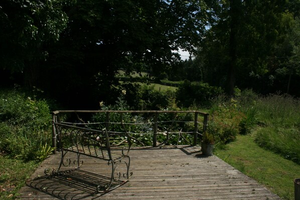 A wooden deck with a metal bench and a potted plant. - Water Farm House, Stowting (Stowting)