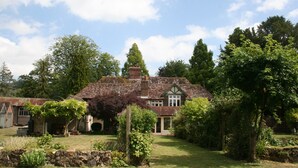 A traditional house with a stone foundation, a brick chimney, and a well-maintained garden with various plants and a stone wall. - Water Farm House, Stowting (Stowting)