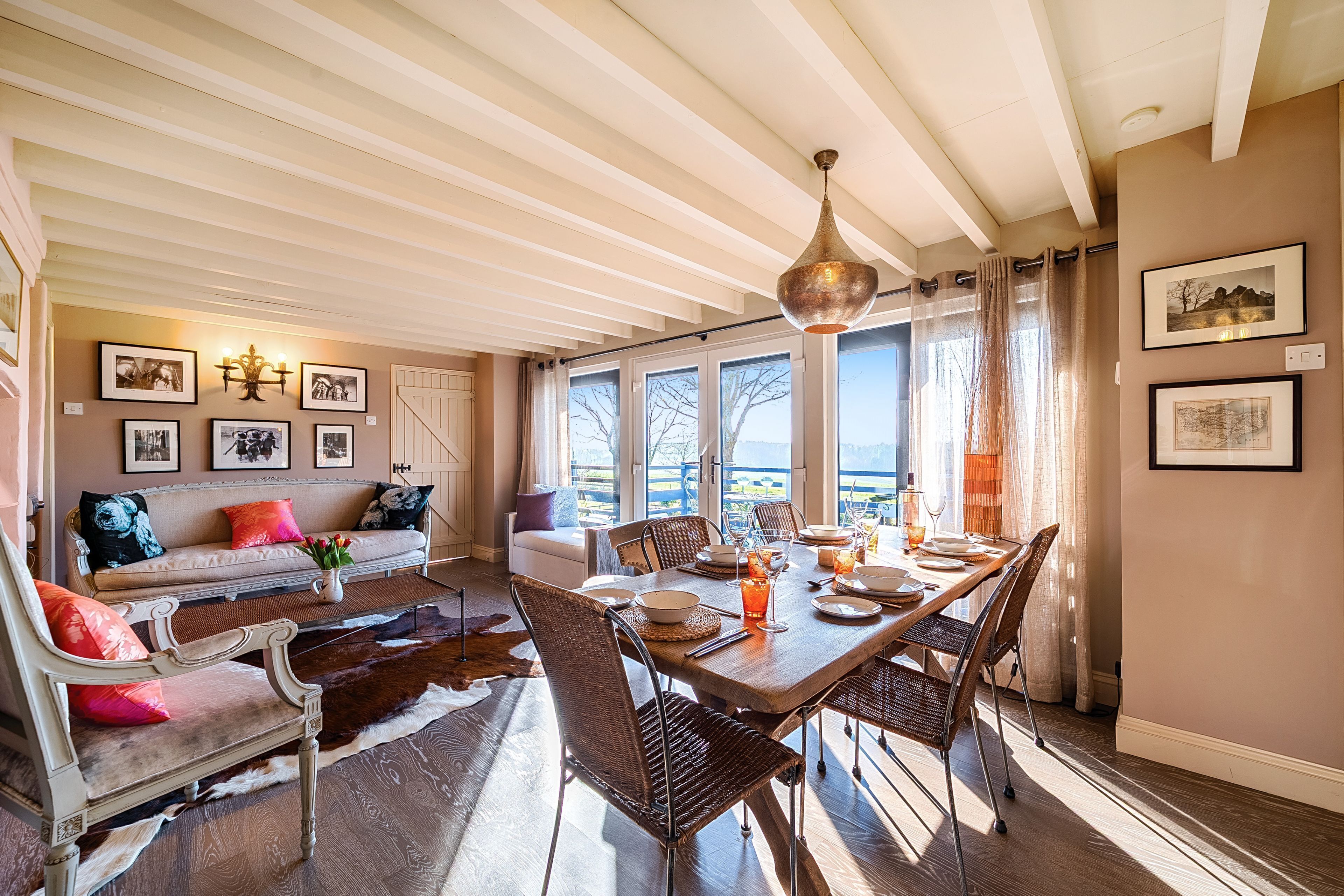 Un coin repas avec une table en bois dressée pour quatre personnes, entourée de chaises en osier.