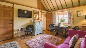 A cozy room with a wooden ceiling, a dining table with chairs, a pink sofa, and a fluffy rug. - Pond Cottage, Egerton (Egerton)