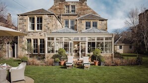 A stone house with a conservatory, outdoor seating, and a well-maintained lawn. - Private and Prestigious Luxury Home (Edinburgh)