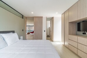 A modern bedroom with a large bed, built-in wooden wardrobe, and a television. - |Ahead| Stylish 2BR with Parking (Bogotá)