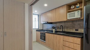 Una cocina moderna con armarios de madera, microondas y refrigerador de acero inoxidable.