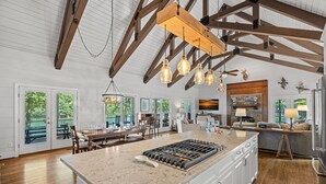 A spacious kitchen with a large island, wooden beams, and pendant lighting. - Blissfully Together- Blue Heron + Back Porch Sleeps 22 (Mooresville)