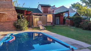 A backyard with a swimming pool, a covered patio, and a brick wall. - Nancy and Carlos's house, view of the mountains, swimming pool and barbecue area. (San Luis)
