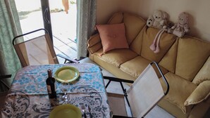 A cozy living area with a sofa, a dining table with a bottle and glass, and a chair. - Nancy and Carlos's house, view of the mountains, swimming pool and barbecue area. (San Luis)