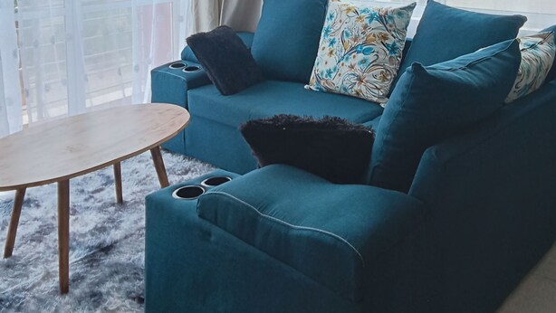 A living room with a teal sofa, a small wooden table, and a furry rug. - 5 minutes to Ngong hills! Family-sized condo with gym , supermarket $ school (Nairobi)