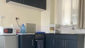 A compact kitchen with a microwave, stove, and cabinets. - 5 minutes to Ngong hills! Family-sized condo with gym , supermarket $ school (Nairobi)