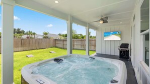A hot tub in a covered outdoor area with a wooden fence and a grassy lawn in the background. - Art Deco~Miami~Jacuzzi~Game Room~2 min. to Beach! (Panama City Beach)