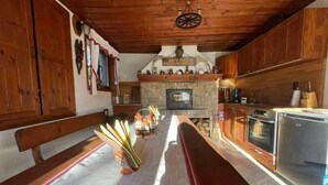 A rustic kitchen with wooden cabinets, a stone fireplace, and a bench. - Villa White Stone - Zlatograd (Zlatograd)