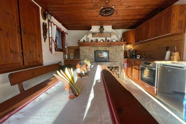 Una cocina rústica con armarios de madera, una chimenea de piedra y un banco.