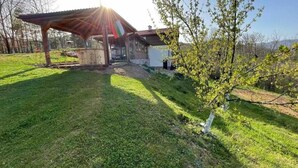 A covered outdoor area with a building, a grassy lawn, and a tree. - Villa White Stone - Zlatograd (Zlatograd)