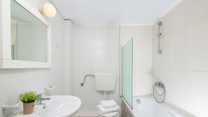 A modern bathroom with a sink, toilet, and bathtub. - Spacious Apartment with Sea View & Shared Pool (Hersonissos)