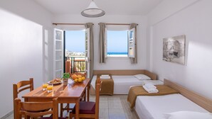 Ein Hotelzimmer mit Essbereich, zwei Betten, Meerblick und einem Bild an der Wand.
