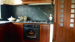 A kitchen with dark wooden cabinets, a black countertop, a stove, an oven, and a decorative sign. - THE SWEET VILLA - A charming place of Mediterranean quiet. (Santa Maria di Castellabate)