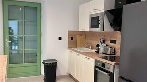 Une cuisine de taille réduite, avec des meubles blancs, un four à micro-ondes, un grille-pain et un réfrigérateur.